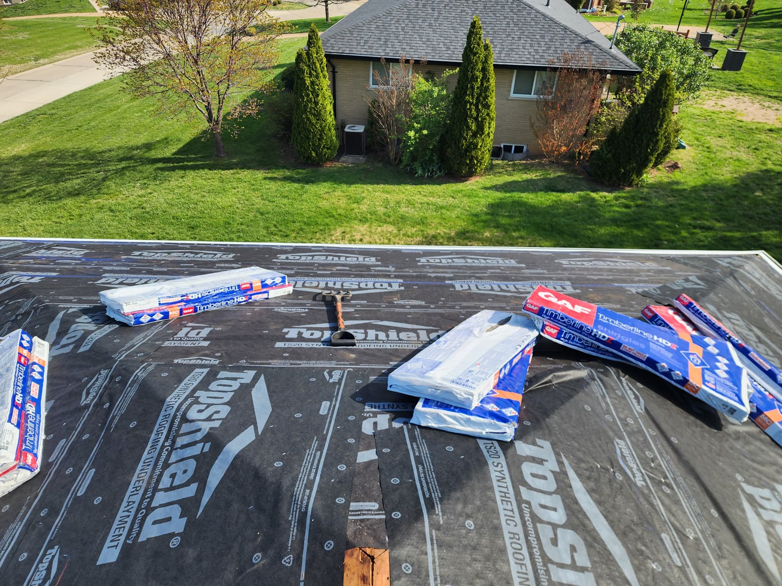 Synthetic roofing underlayment with shingle bundles staged